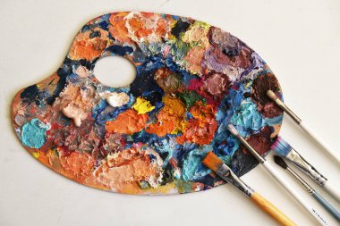 Sanat paletine yakın çekim. Yağlı boyaların parlak noktaları. kullanılmış palet. çok renkli boyalar var. Mesaj için yer var. boya fırçaları