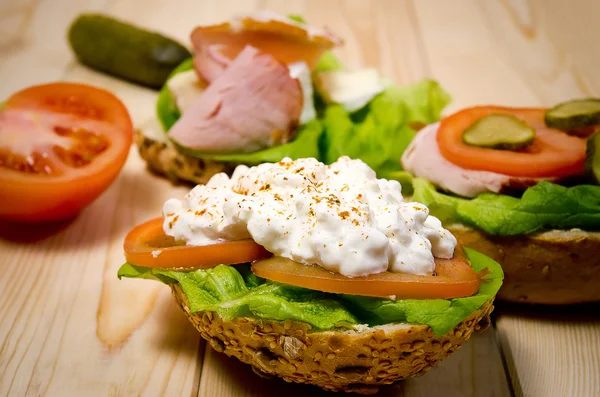 Closeup of homemade sandwich with ham, cottage cheese, fresh tomato and green salad on wooden table — Stock Fotó