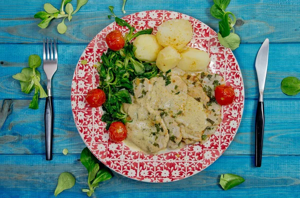 Closeup of Roast turkey with potatoes and rucola, tomatoes on blue wooden table