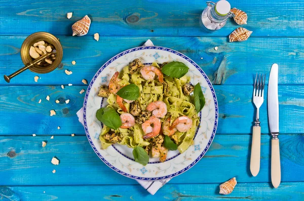 Tagliatelle pasta with shrimps, nuts and chicken on wooden table — Zdjęcie stockowe