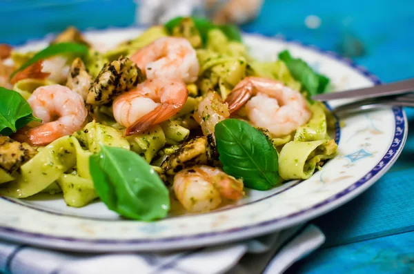 Closeup of tagliatelle pasta with shrimps, nuts and chicken on wooden table