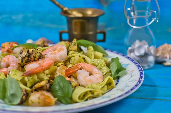 Closeup of tagliatelle pasta with shrimps, nuts and chicken on wooden table