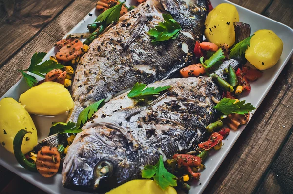 Closeup of grilled dorada garnished with potato and vegetables