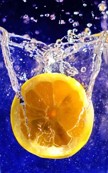 Fresh half f lemon in the splashes of water on a dark blue background
