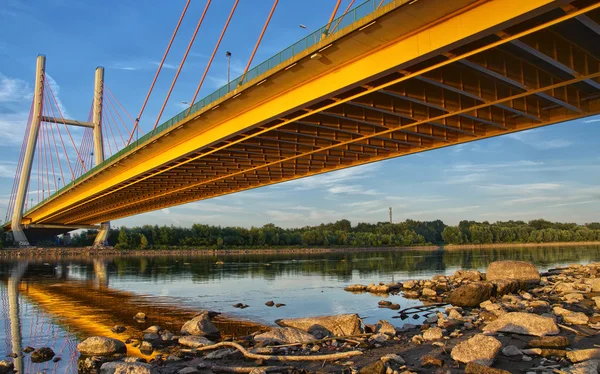 Backlit bridge at night and reflected in the water.Siekierkowski bridge