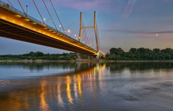 Backlit bridge at night and reflected in the water.Siekierkowski bridge — Zdjęcie stockowe