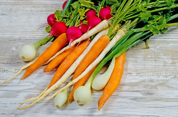 Verduras jóvenes de primavera sobre fondo de madera. Las zanahorias, el rábano, el perejil - la cosecha fresca del jardín — Foto de Stock
