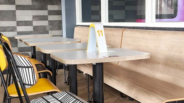 Ahşap Masalar ve Sarı Sandalyeler ile Kafe Oturma Alanı