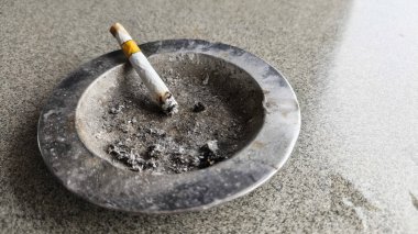 Cigarette Butt in Ashtray Close Up on Concrete Floor