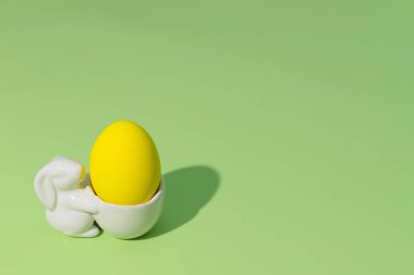 Yeşil arka planda yumurta standındaki paskalya sarısı yumurta. Tebrik kartı.