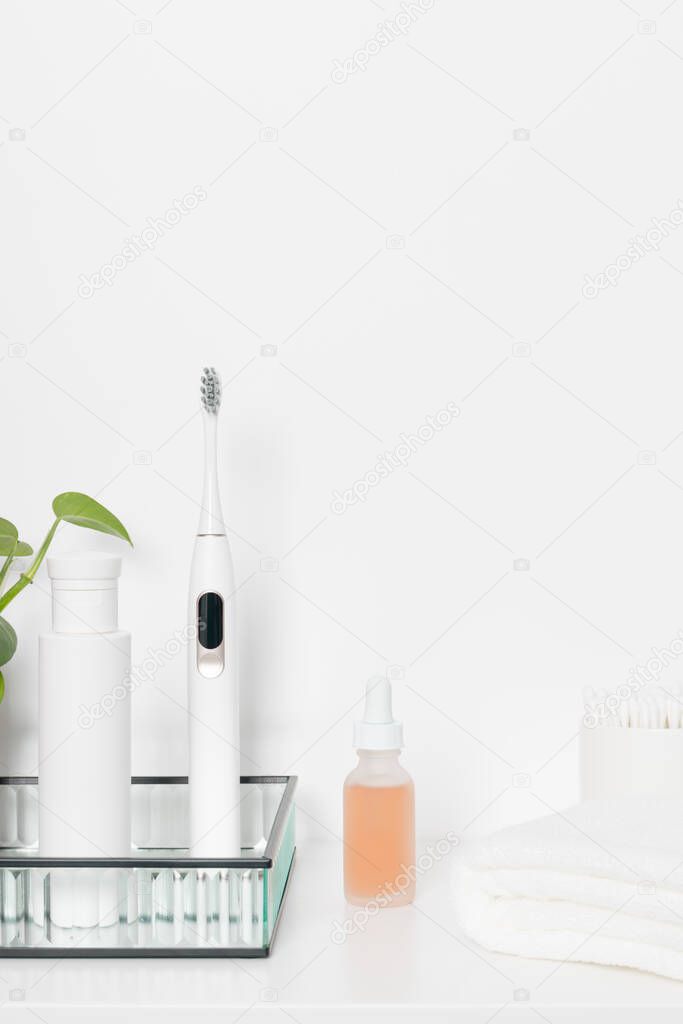 Beauty health care composition with ear sticks, towel, tonic and serum on a white table. Women's beauty treatment routine concept.