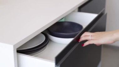 Kadın elleri mutfak dolabını açarken tabağı alıyor.