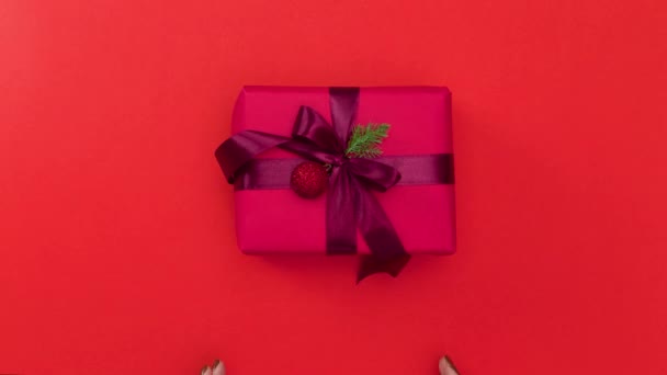 女性的手把圣诞礼物放在红色背景上 停止动作动画 — 图库视频影像