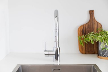 Tahta kesme tahtası ve bitki beyaz bir mutfakta musluğu olan metal bir lavabonun yanında. Yüksek kalite fotoğraf