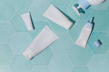 Flat Lay of White Cosmetic Tubes on Mint Green Tile Background. Cosmetic product advertising, packaging mockups, spa or wellness promotions 