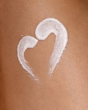 Bir kadın derisinin derisinden deri yüzen vücut fırçasıyla yakın çekim makro görüntüsü. Görünür parçacıklara sahip kremsi beyaz doku cilt bakımını ve güzellik kavramlarını vurgular.