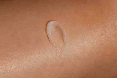 Bir kadının tenine sürülen cilt kreminin makro görüntüsü. Kozmetik cilt ürünü dokusu. Yüz kremi, vücut losyonu sürgüsü. 