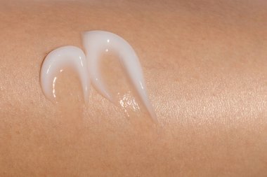 Bir kadının tenine sürülen cilt kreminin makro görüntüsü. Kozmetik cilt ürünü dokusu. Yüz kremi, vücut losyonu sürgüsü. 