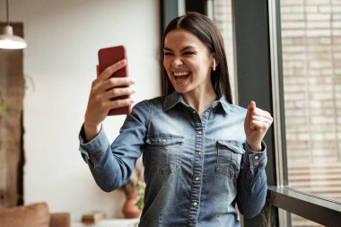 Kablosuz kulaklıklı heyecanlı kadın müzik dinliyor ve akıllı telefona bakıyor. 