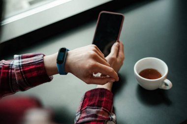 Bileğinde cep telefonu olan akıllı bir kadının görüntüsü. 