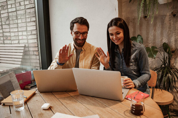 счастливые фрилансеры размахивают руками, пользуясь ноутбуками на столе