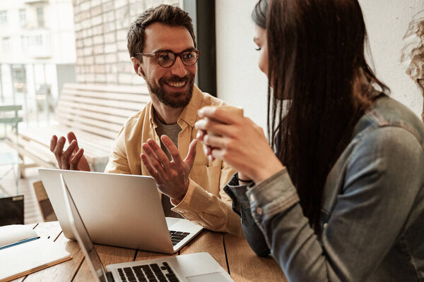 веселые фрилансеры беседуют возле ноутбуков на столе