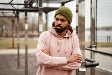 Üzgün Afro-Amerikan sporcusu spor sahasında çapraz silahlarla duruyor.