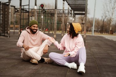 Genç Afrikalı Amerikalı sporcu, stadyumdaki arkadaşıyla konuşurken elini işaret ediyor.