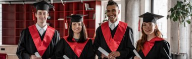 happy interracial students in graduation gowns and caps holding diploma, prom 2021, banner clipart