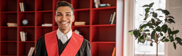 happy african american student in graduation gown, banner
