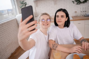 Mutlu lezbiyen çift mutfakta selfie çekiyor. 