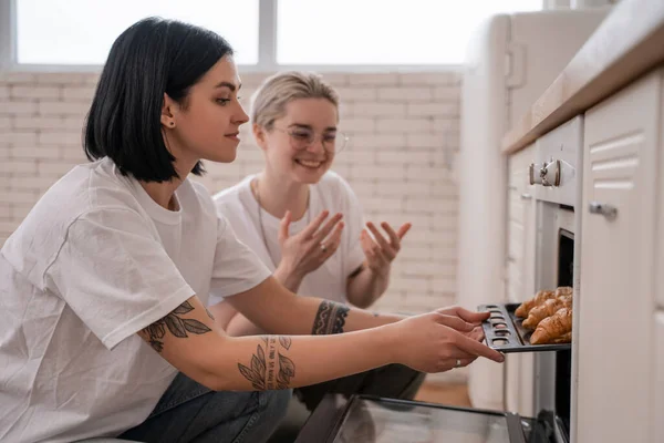 Pareja Lesbiana Tatuada Tomando Bandeja Horno Con Croissants Recién Horneados — Foto de Stock