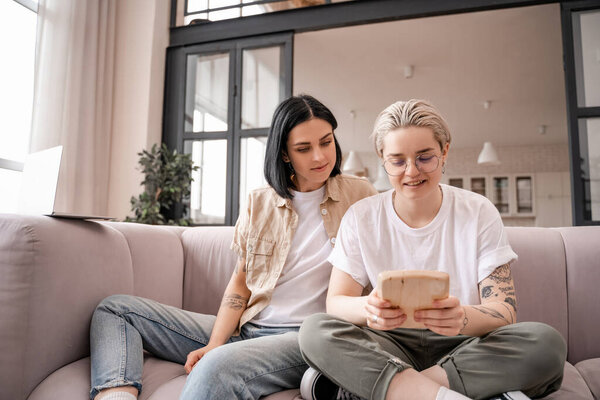 лесбиянка играет на мбире, сидя на диване с подругой 