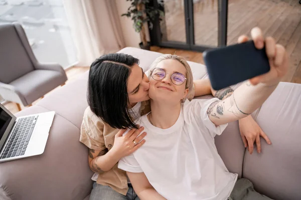 Woman Kissing Cheek Happy Girlfriend Glasses Taking Selfie Living Room — Stock Photo, Image