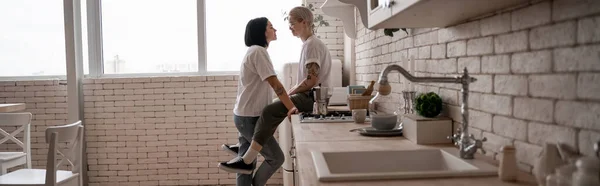 Mujer Joven Sentada Mesa Cocina Mirando Novia Cerca Cafetera Estufa — Foto de Stock