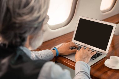 Bulanık iş adamı jet uçağında kahvenin yanında laptop kullanıyor. 