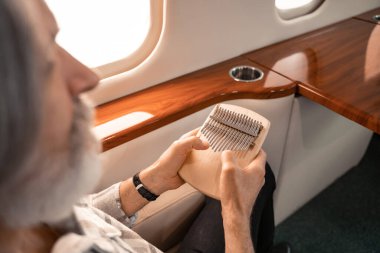 Mbira, özel uçakta bulanık ön plandaki olgun bir adamın ellerinde. 