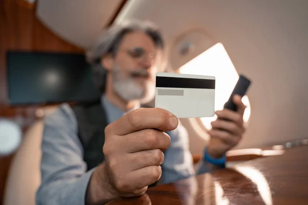在喷气式飞机上 商人在模糊背景下使用智能手机的信用卡 — 图库照片