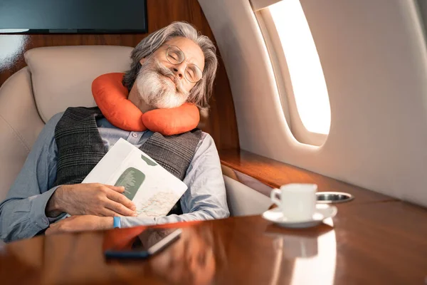 Businessman Neck Pillow Holding Magazine While Sleeping Coffee Smartphone Plane — Stock Photo, Image