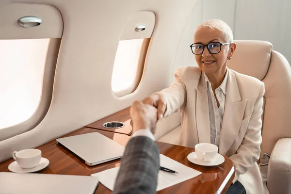 Smiling Businesswoman Shaking Hands Businessman Paper Laptops Private Jet — Stock Photo, Image