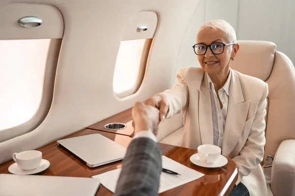 Lächelnde Geschäftsfrau Schüttelt Geschäftsmann Der Nähe Von Papier Und Laptops — Stockfoto