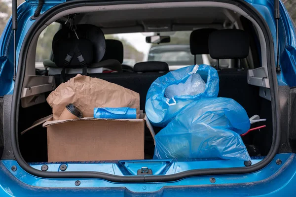 carton box with paper cup near trash bags in modern car