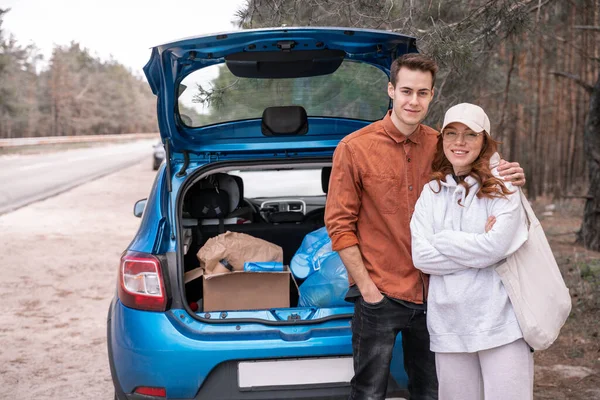 Happy Man Hugging Woman Glasses Cap Car Trash Woods — Stock Photo, Image