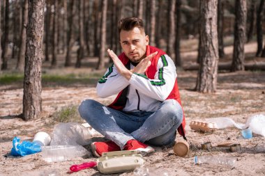 Bacak bacak üstüne atmış bir adam oturuyor ve yerde çöp izine rastlamıyor.