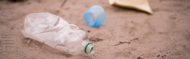 Plastik şişe, bulanık kum ve pankartın yanında.