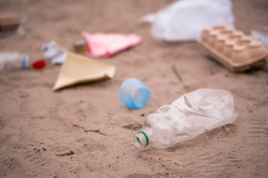 Plastik şişe, kumdaki bulanık çöpün yanında.