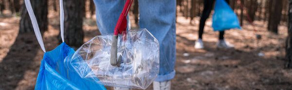 cropped view of volunteer picking up rubbish in forest, banner