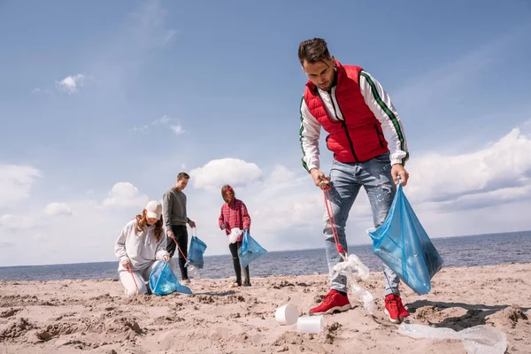 Jovem Segurando Saco Lixo Coletando Lixo Areia Perto Voluntários — Fotografia de Stock
