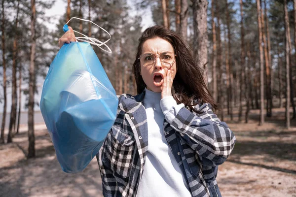 Scioccato Giovane Donna Possesso Sacchetto Blu Spazzatura Nella Foresta — Foto Stock