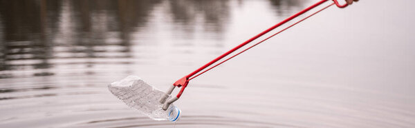 grabber picking up plastic bottle from lake, banner